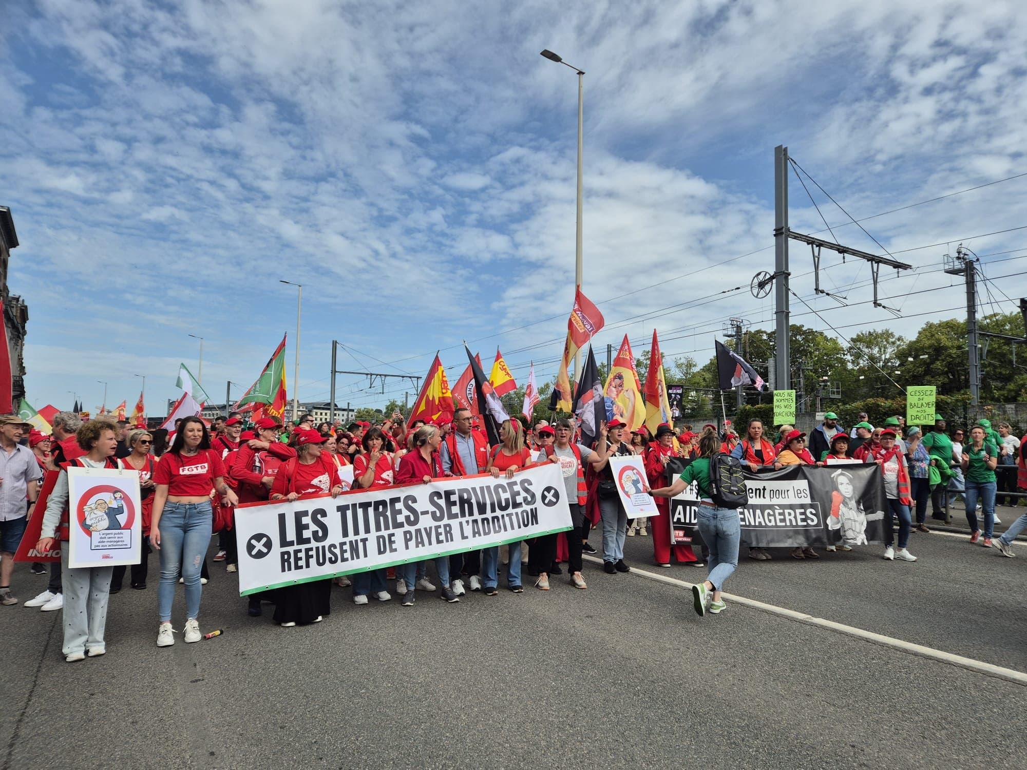 Tête de cortège à Namur : des dizaines de manifestants derrière une banderole, drapeaux levés.